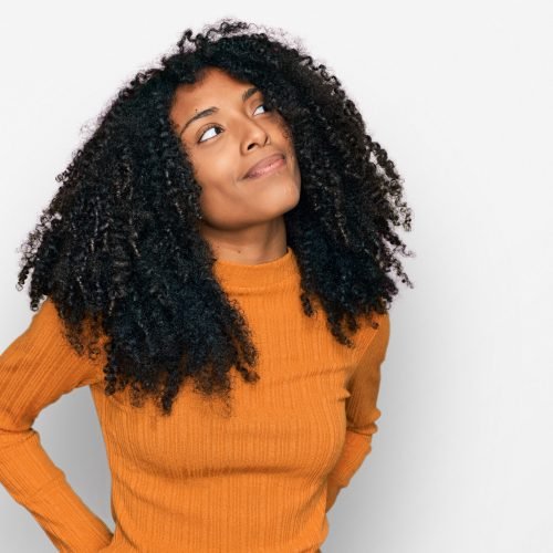 Young african american girl wearing casual clothes smiling looking to the side and staring away thinking.